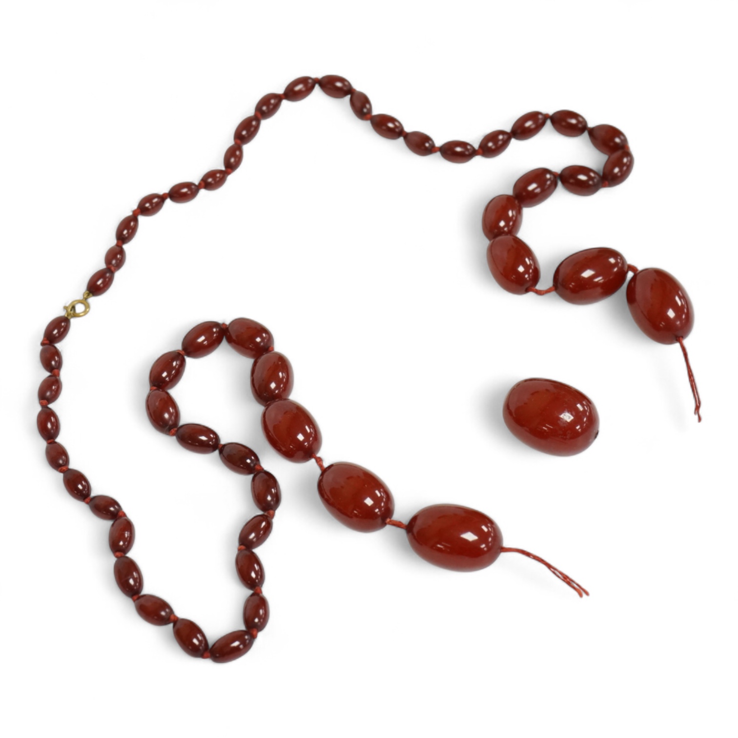 A single strand graduated simulated oval cherry amber bead necklace, string broken, gross weight 73 grams.